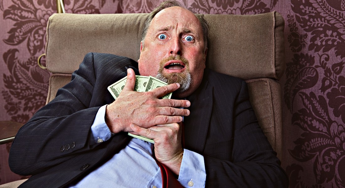 Photo of a guy holding on to money looking frightened