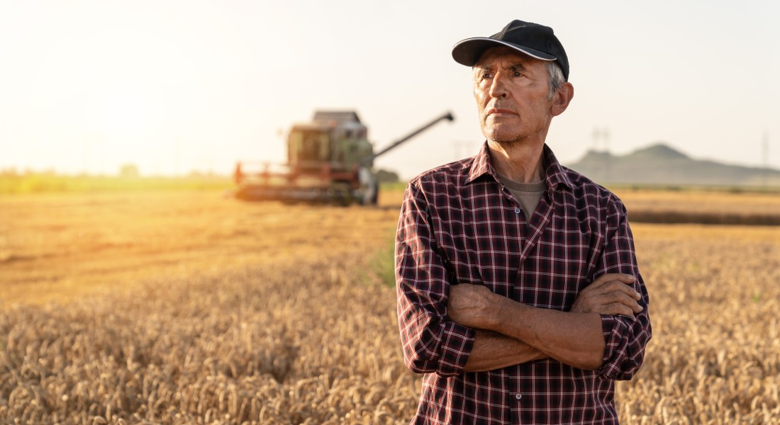 Photo of a famer looking over his crops while thinking