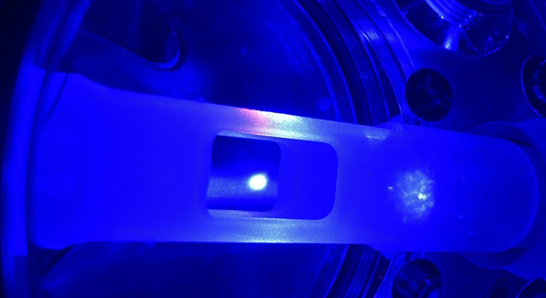 A small glowing dot in a chamber bathed in blue light.
