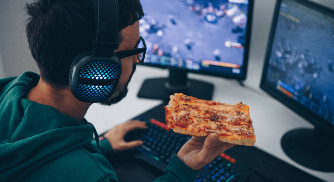 man eating a pizza while gaming