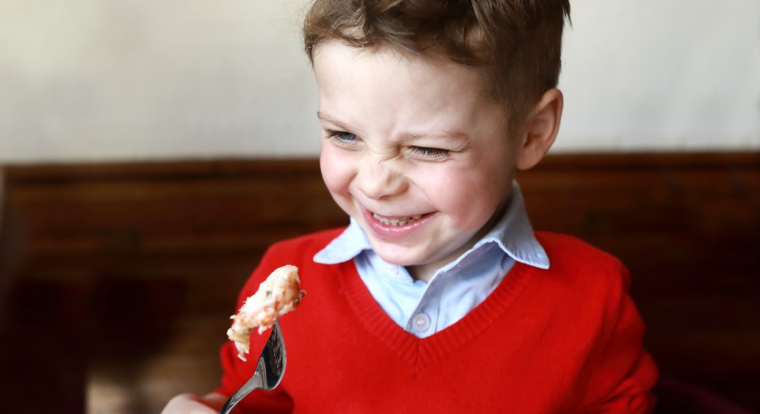 Foto af en dreng, der smiler, mens han kigger på sin gaffel med fisk på