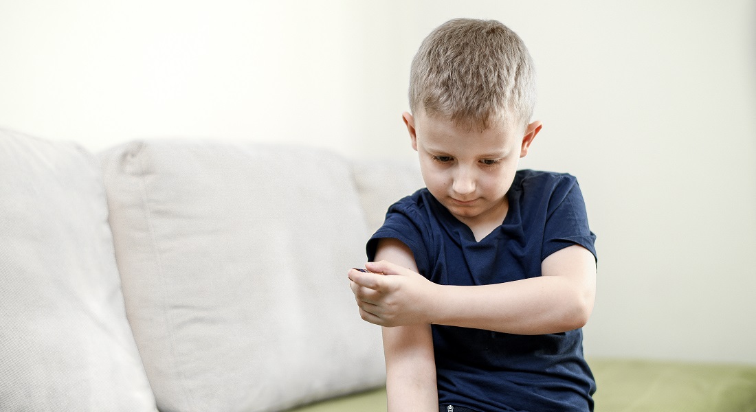 Barn stikker sig i armen med en insulinsprøjte